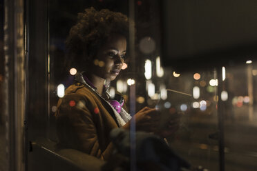 Young woman with tablet waiting at the tram stop by night - UUF09815