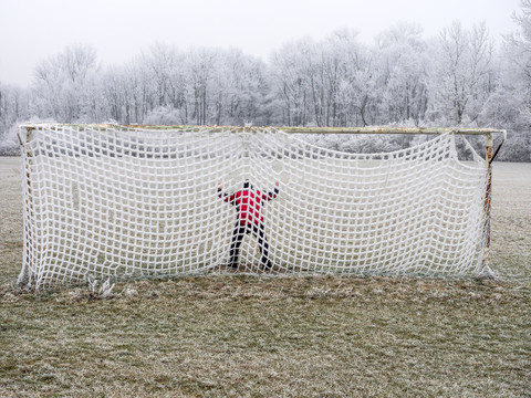 Mann im Fußballtor im Winter, lizenzfreies Stockfoto