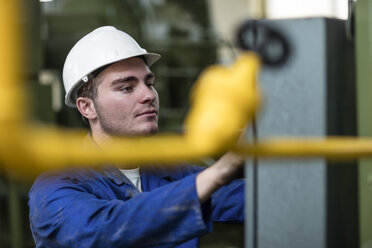 Arbeiter, der eine Maschine in einer Fabrik bedient - ZEF12400