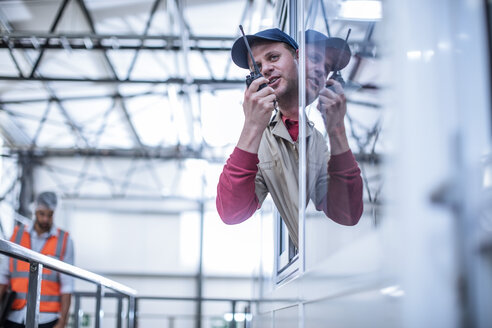 Arbeiter mit Walkie-Talkie bei der Einweisung in einer Fabrik - ZEF12434