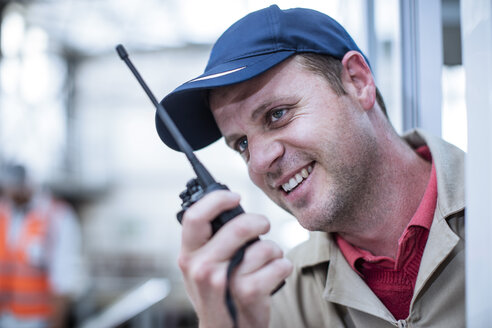 Smiling worker with walkie-talkie in factory - ZEF12435