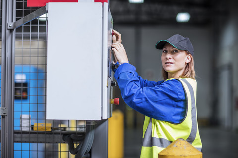 Weiblicher Arbeiter, der eine Maschine in einer Fabrik bedient, lizenzfreies Stockfoto