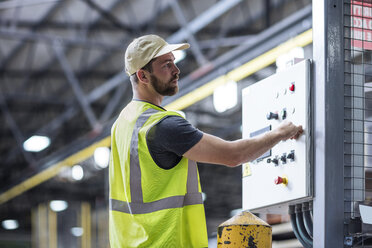 Arbeiter, der eine Maschine in einer Fabrik bedient - ZEF12448