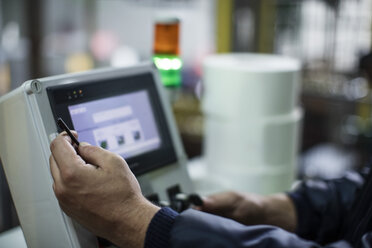 Close-up of worker operating machine in factory - ZEF12451