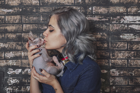 Junge Frau küsst Sphynx-Katze, lizenzfreies Stockfoto