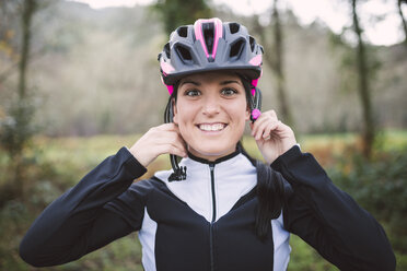 Porträt einer lächelnden Frau, die einen Fahrradhelm aufsetzt - RAEF01650