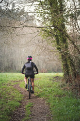 Mountainbikerin fährt mit ihrem Fahrrad auf einem Weg - RAEF01658