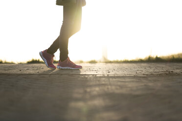 Woman wearing sneakers strolling at sunset, partial view - CHPF00365