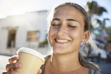 Porträt einer lächelnden jungen Frau mit Kaffee zum Mitnehmen - SRYF00198