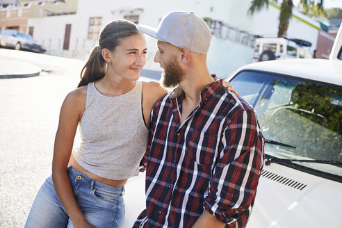 Young couple in love sitting on car bonnet - SRYF00207