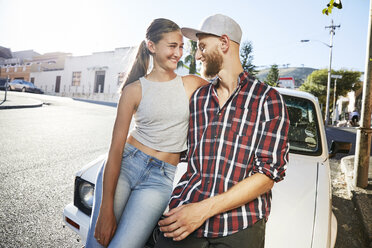 Young couple in love sitting on car bonnet - SRYF00208