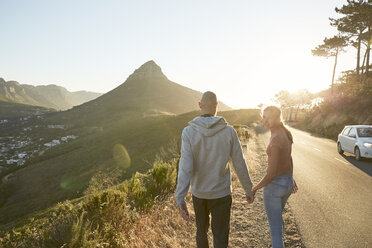 Südafrika, Kapstadt, junges Paar geht Hand in Hand am Straßenrand - SRYF00235
