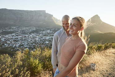 South Africa, Cape Town, happy young couple at roadside at evening twilight - SRYF00236