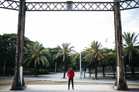 Junger Mann in einem Park mit rotem Kapuzenpulli, lizenzfreies Stockfoto