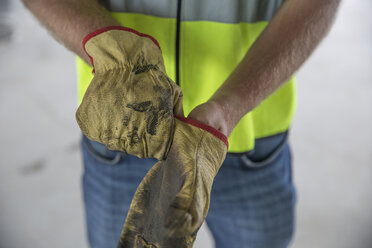 Bauarbeiter zieht Schutzhandschuhe an - ZEF12471