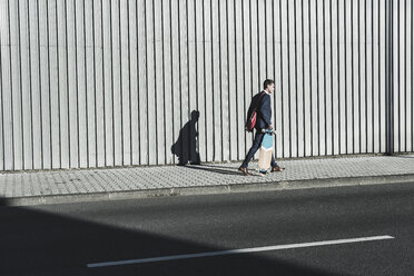 Junger Geschäftsmann mit Skateboard auf dem Bürgersteig - UUF09821