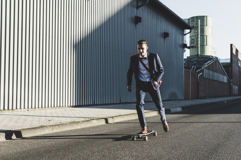 Young businessman riding skateboard on the street stock photo