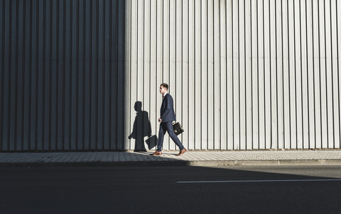 Young businessman walking on pavement stock photo