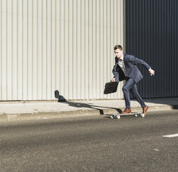 Young businessman riding skateboard on the street - UUF09841