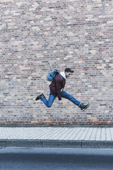 Junger Mann springt vor eine Ziegelmauer - UUF09845