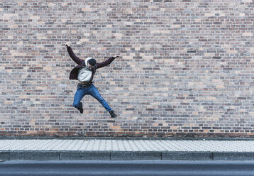 Junger Mann springt vor eine Ziegelmauer - UUF09847