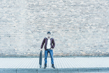 Portrait of young man with skateboard in front of brick wall - UUF09854