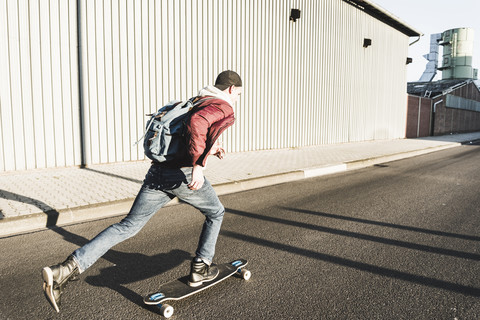 Junger Mann fährt Skateboard auf der Straße, lizenzfreies Stockfoto