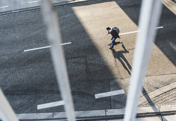 Draufsicht auf einen jungen Mann, der auf der Straße Skateboard fährt - UUF09865