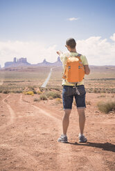 USA, Utah, Rückenansicht eines Mannes mit Rucksack, der auf das Monument Valley zeigt - EPF00276