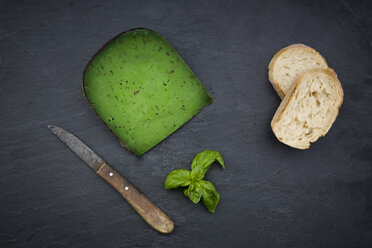 Piece of basil cheese, kitchen knife, slices of white bread and basil leaves on slate - LVF05794