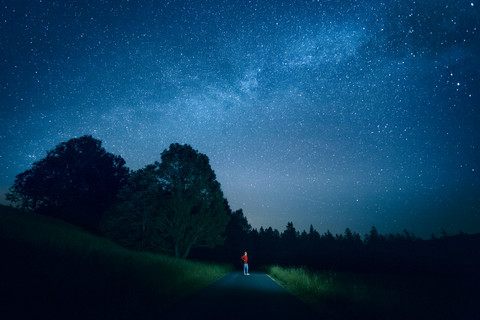 Österreich, Mondsee, junger Mann steht auf leerer Straße unter Sternenhimmel, lizenzfreies Stockfoto