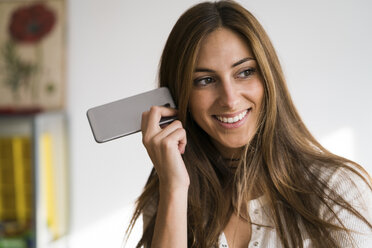 Lächelnde junge Frau mit Mobiltelefon in der Hand - KKAF00331