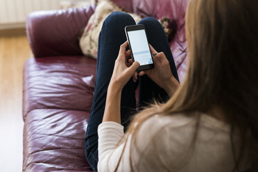 Young woman on couch text messaging - KKAF00333