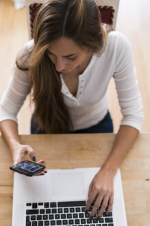 Junge Frau mit Mobiltelefon und Laptop - KKAF00335