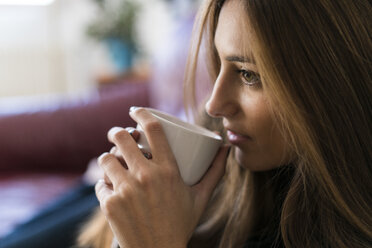 Junge Frau trinkt Kaffee aus einer Tasse - KKAF00341