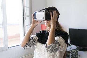 Young woman wearing VR glasses at home - KKAF00346