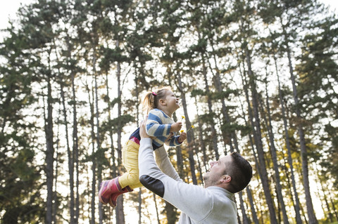 Father lifting up his daughter in forest stock photo