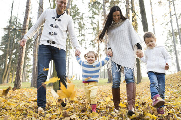 Glückliche Familie mit zwei Mädchen beim Spaziergang im Herbstlaub - HAPF01316