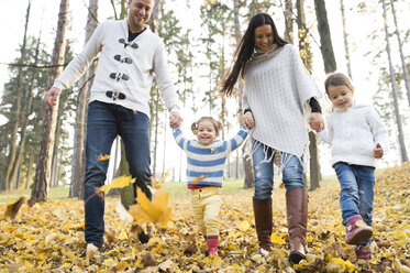 Happy family with two girls walking in autumn leaves - HAPF01316