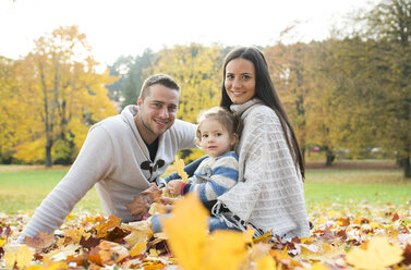 Glückliche Familie im Herbstlaub sitzend - HAPF01321