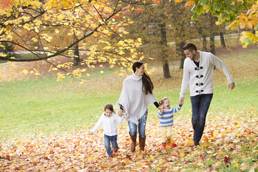 Glückliche Familie mit zwei Mädchen beim Spaziergang im Herbstlaub - HAPF01322