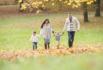 Happy family with two girls walking in autumn leaves - HAPF01323