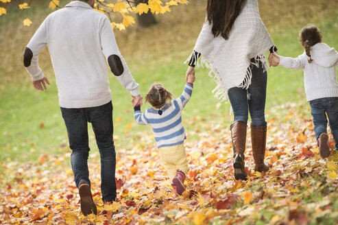 Glückliche Familie mit zwei Mädchen beim Spaziergang im Herbstlaub - HAPF01324