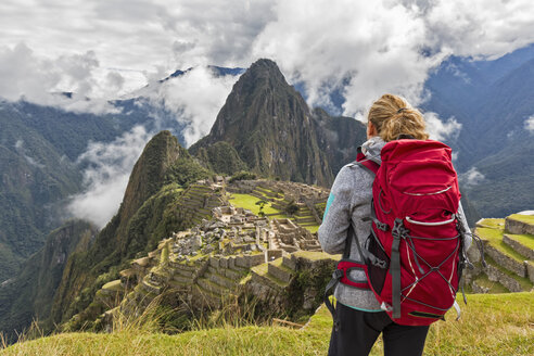 Peru, Anden, Urubamba-Tal, Tourist mit rotem Rucksack am Machu Picchu mit Berg Huayna Picchu - FOF08776