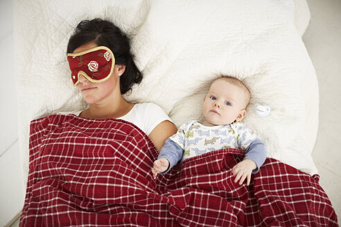 Mutter mit Schlafmaske und wachem Baby im Bett liegend - FSF00655