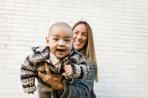 Glückliche Mutter mit Baby an der Backsteinmauer, lizenzfreies Stockfoto