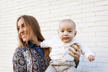 Glückliche Mutter mit Baby an der Backsteinmauer - VABF01033