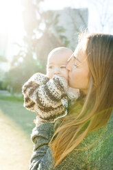 Mother kissing baby in park - VABF01049