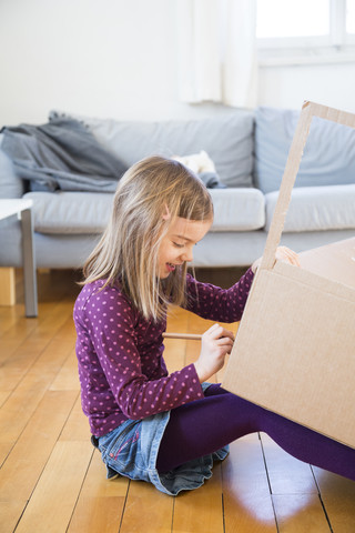 Mädchen bastelt zu Hause an einem Karton, lizenzfreies Stockfoto