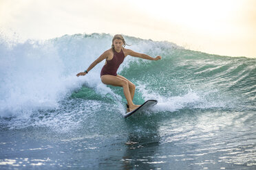 Indonesien, Bali, Frau surft auf einer Welle - KNTF00615